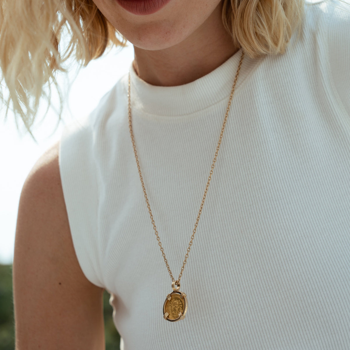 A solid 23k yellow gold vintage greek coin in a yellow gold bezel setting