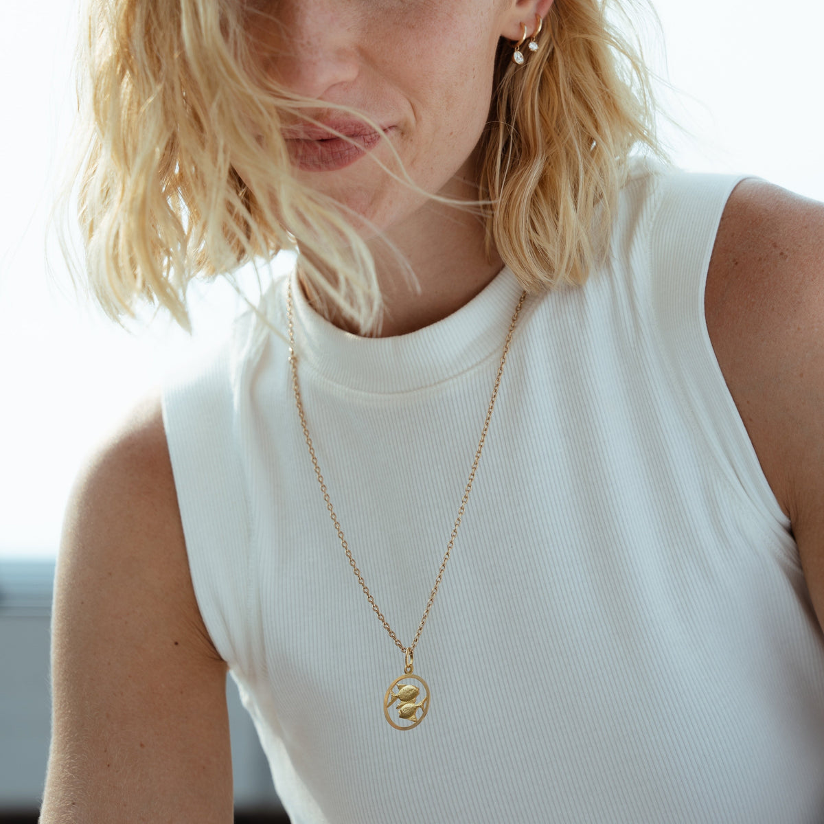 A solid gold 18k pisces charm cutout