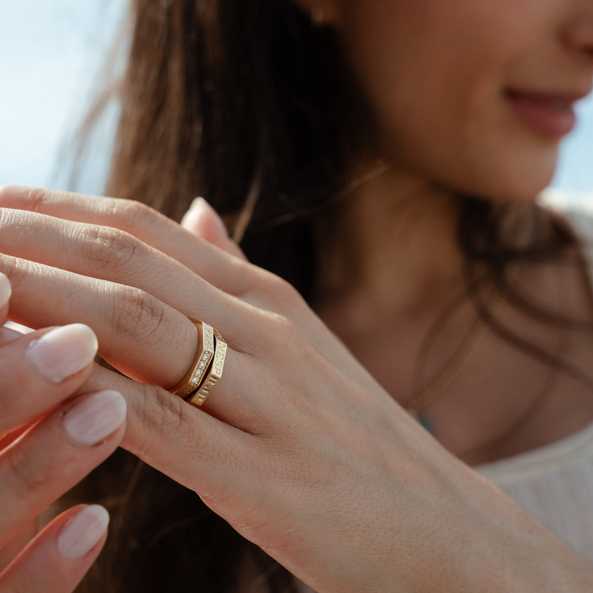 Close-up of a woman's hand wearing two family rings with personal hand engraving and diamonds