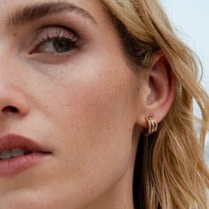 Close-up of a pave diamond triple huggies in the Fewer Finer Signature trapezoid shape that hugs the ear