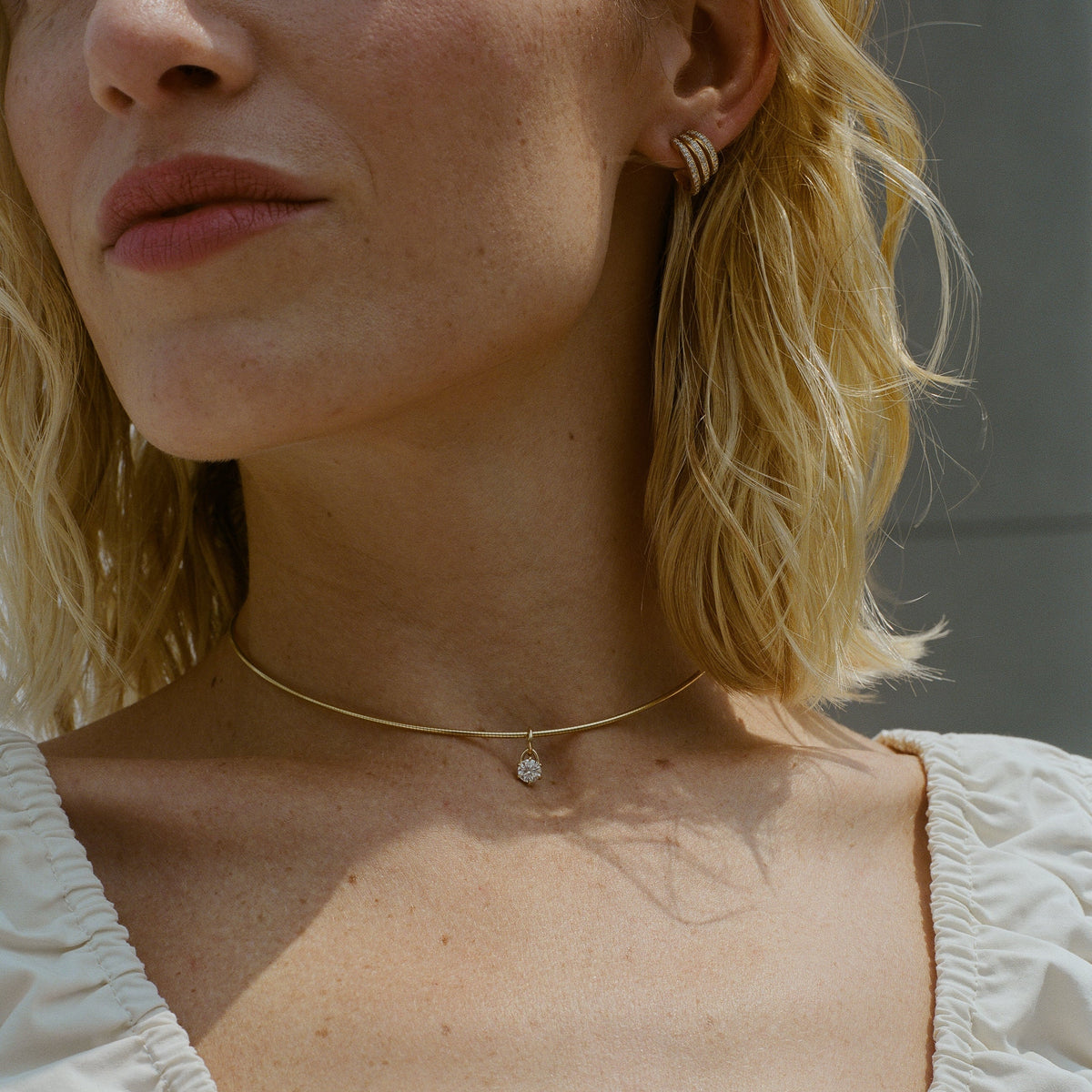Close-up of a thin 1.5mm omega chain in solid gold with a 6-prong 0.5 ct diamond charm that can be used with natural or lab diamonds