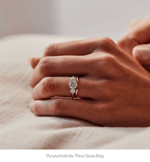 Model wearing 14k gold rounded band open spacer ring with diamonds stacked with Three Stone engagement ring