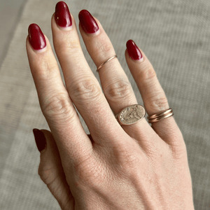 Model wearing 14k solid gold oval signet ring with custom hand engraved pet portrait and gemstones