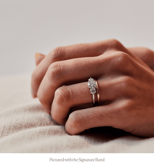 Model wearing the 14k gold three stone diamond engagement ring stacked with the Signature Band
