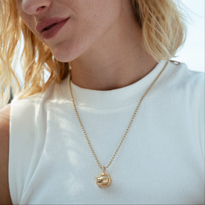 Vintage gold orb locket charm that opens to reveal a four-photo folding locket with engravable gold panels.