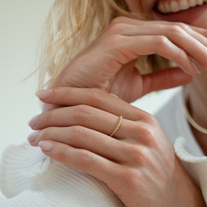 A solid gold twisted ring to resemble rope made for stacking or as a minimal dainty style on its own