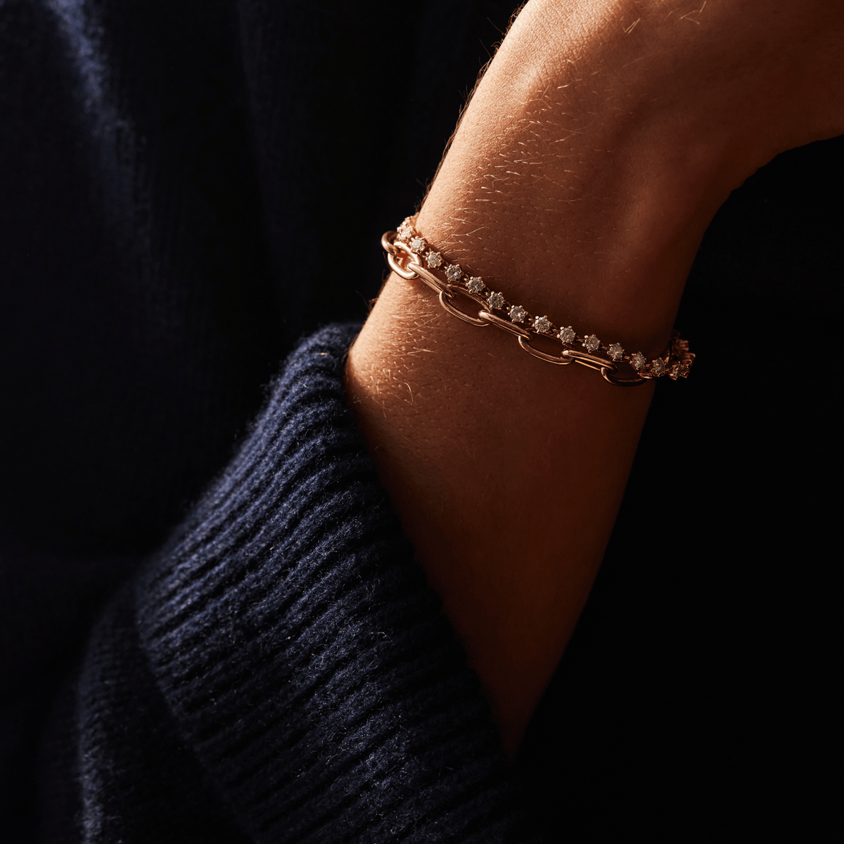 Model wearing the 14k gold tennis bracelet with birdie-shaped links with diamonds stacked with the Perfect Charm Bracelet