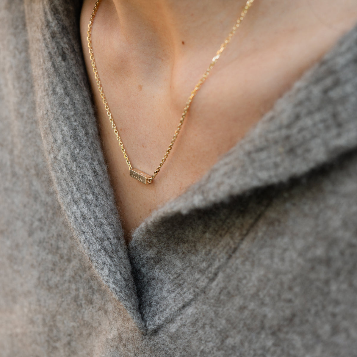 Model wearing 14k gold hand engraved gold bar necklace