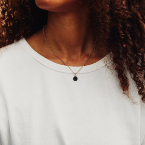 Model wearing the 14k solid gold engravable circle charm in size xs on a Caviar Necklace