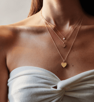 Model wearing all sizes of the 14k solid gold engravable heart charm