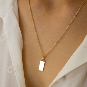 Model wearing 14k solid gold engravable rectangle charm 