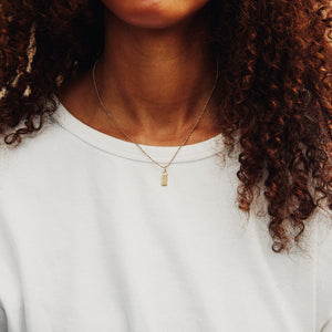 Model wearing extra small 14k solid gold engravable rectangle charm on Caviar Necklace