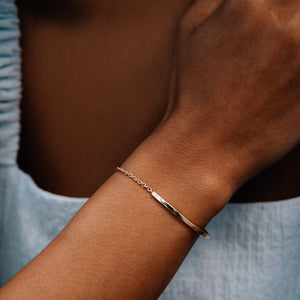 Model wearing the 14k gold chain and cuff bracelet with two flush set diamonds