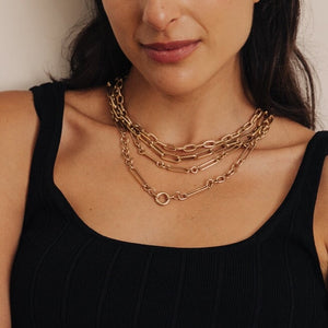 Model wearing chunky mixed link charm necklace styled with other necklaces