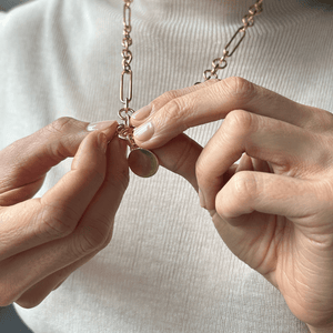 Model adding a charm to the chunky mixed link charm necklace