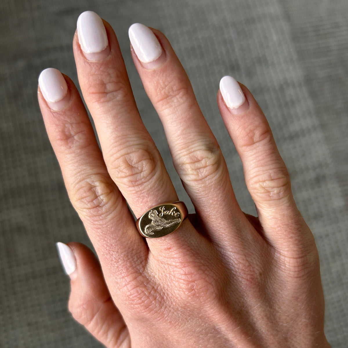 Model wearing 14k solid gold oval signet ring with custom hand engraved pet portrait