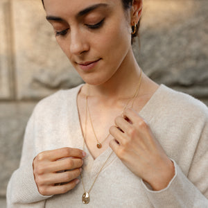 Model wearing 14k solid gold pebble necklace stacked with Worry Stone Necklace