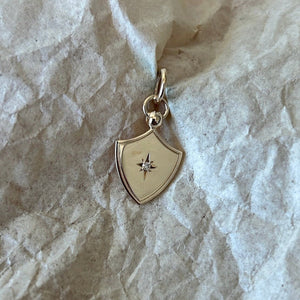 14k gold shield shaped charm with a star set diamond in the middle