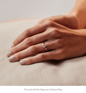 Model wearing a thin 14k gold ring with diamonds stacked with an engagement ring