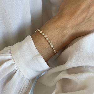 Model wearing the 14k gold diamond tennis bracelet with three alternating setting styles