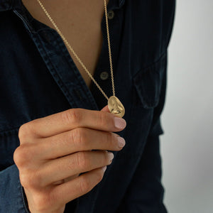 Model wearing 14k solid gold textured worry stone necklace 