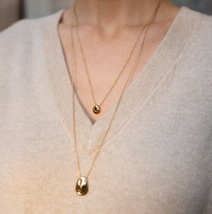 Model wearing 14k solid gold textured worry stone necklace stacked with Precious Pebble Necklace