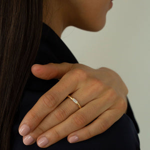 Model wearing rounded 14k gold band with a petite baguette diamond