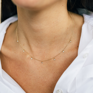 Model wearing 14k gold necklace with bezel set diamonds