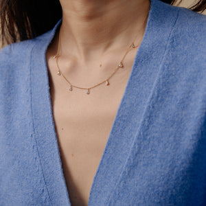 Model wearing 14k gold necklace with bezel set diamonds