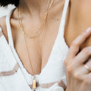 Model wearing the 14k gold long chain link necklace stacked with the Caviar Necklace and Classic Rectangle Charm