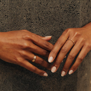 Model wearing a thin 14k gold ring with diamonds